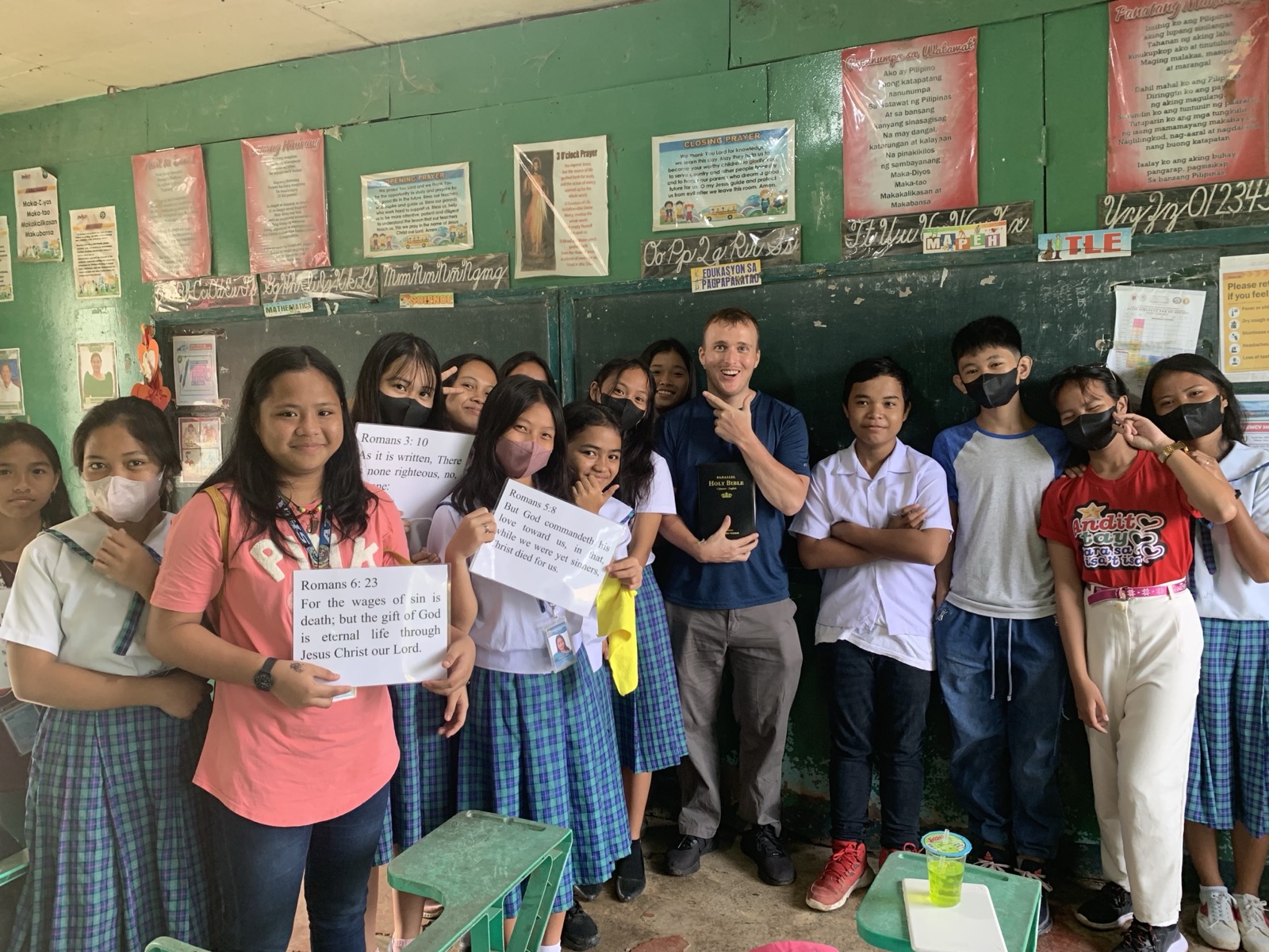 Collin teaching high school students in a Filipino classroom with students holding gospel verse cards