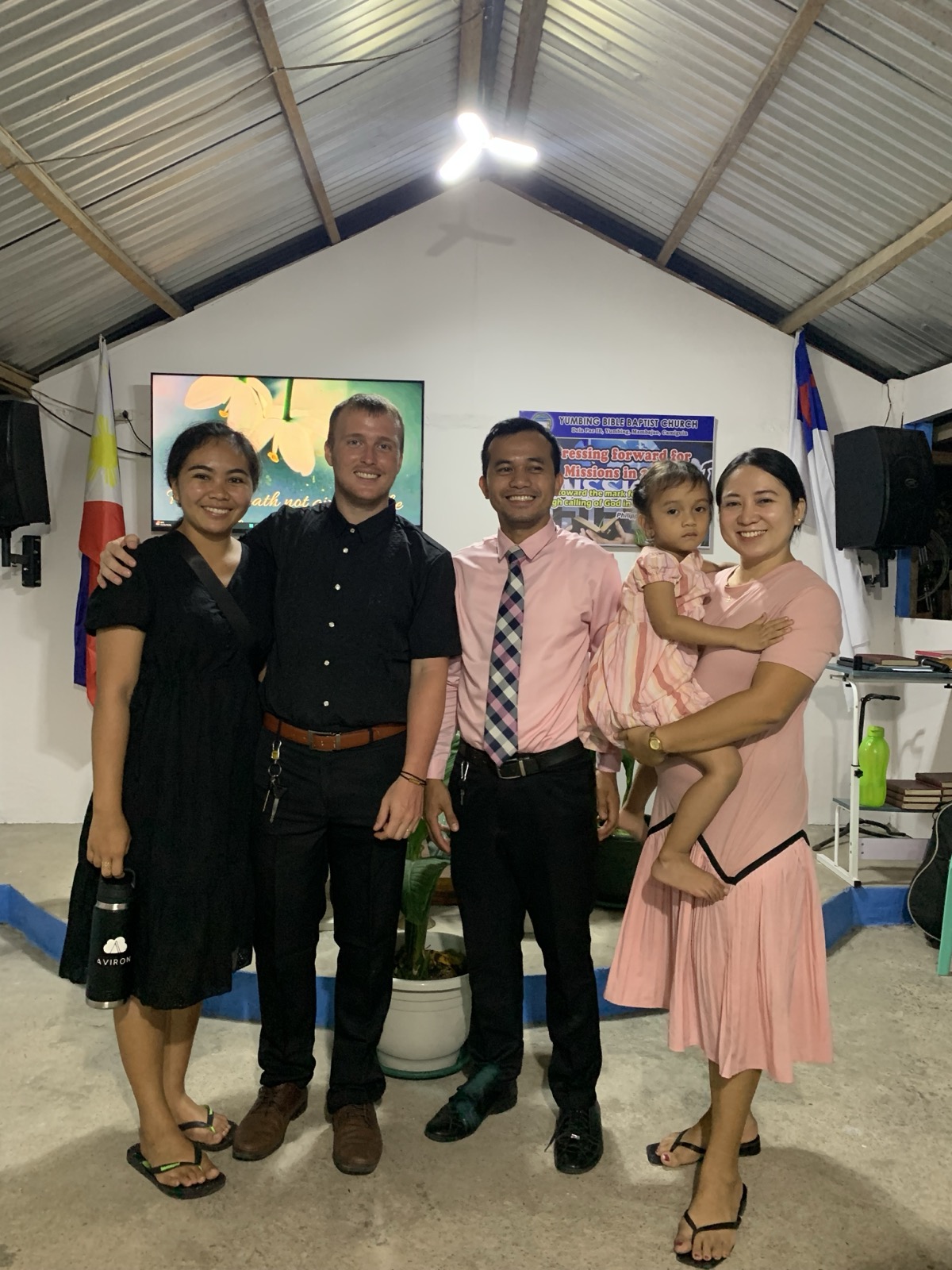 The Schneide family standing with a Bohol pastor and his wife and daughter inside a Filipino Baptist church